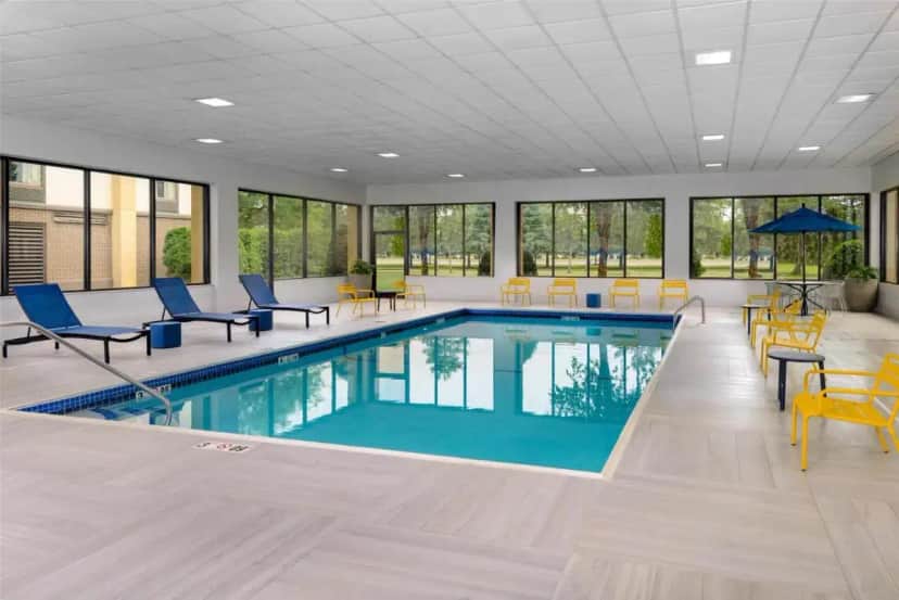 a swimming pool with blue chairs and a table and chairs at Hampton Inn Buffalo-Airport Galleria Mall in Cheektowaga