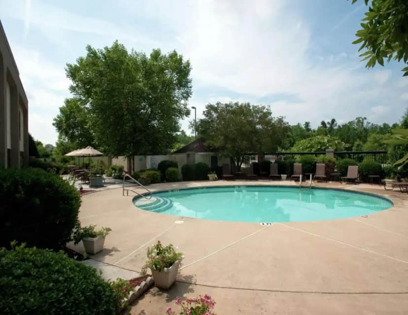 a swimming pool in a yard with chairs and trees at Hampton Inn Concord/Kannapolis in Kannapolis
