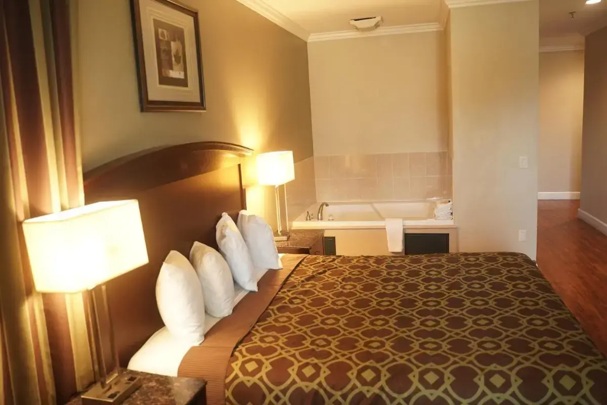 a hotel room with a bed and a bath tub at Harbor Inn & Suites in Anaheim