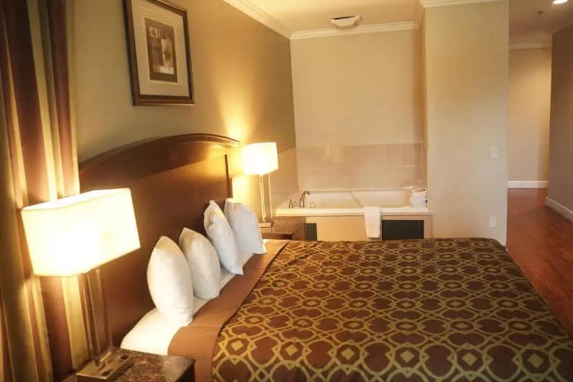 a hotel room with a bed and a bath tub at Harbor Inn & Suites in Anaheim