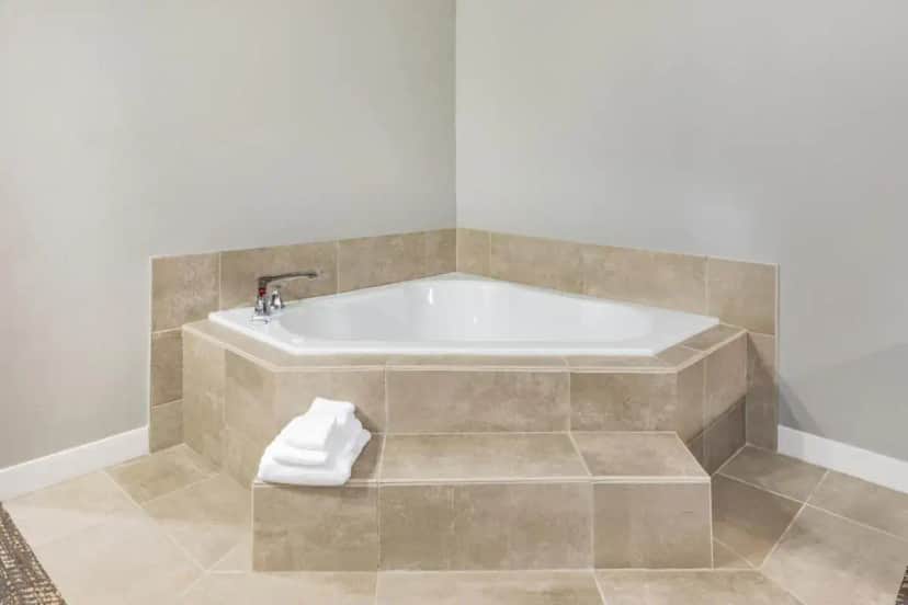 a bathroom with a tub with a towel on the floor at Hawthorn Extended Stay by Wyndham Oklahoma City Airport in Oklahoma City