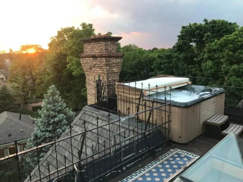 a deck with a hot tub and a chimney at Henderson Castle Inn in Kalamazoo