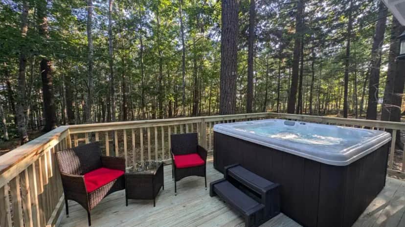 a hot tub on a deck in the woods at Hinckleys Dreamwood Cottages in Bar Harbor