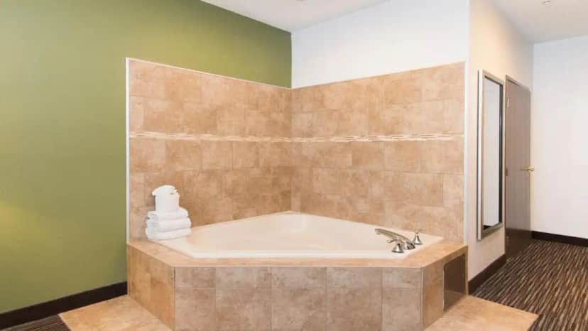 a bath tub in a bathroom with green walls at Holiday Inn Express & Suites Chicago Deerfield Lincolnshire by IHG in Riverwoods