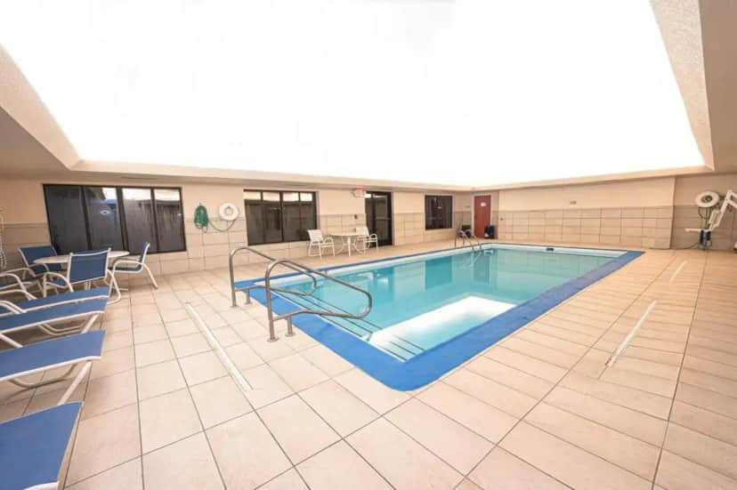 a large swimming pool in a large room with chairs at Holiday Inn Express Hotel & Suites East Lansing by IHG in East Lansing
