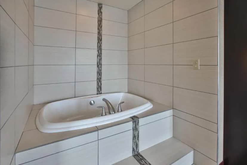 a bath tub in a bathroom with a sink at Holiday Inn Express & Suites Geneva Finger Lakes by IHG in Geneva