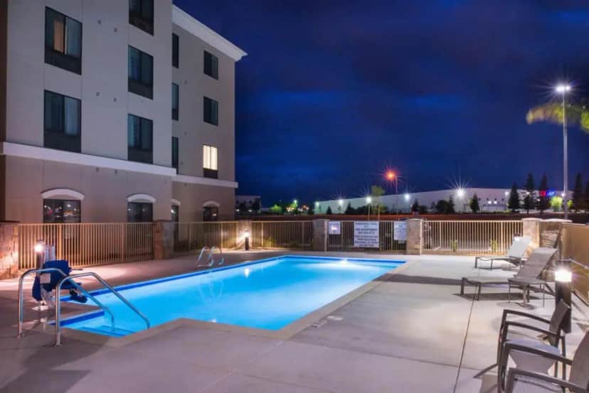 a swimming pool in front of a building at night at Holiday Inn Express & Suites Bakersfield Airport by IHG in Bakersfield
