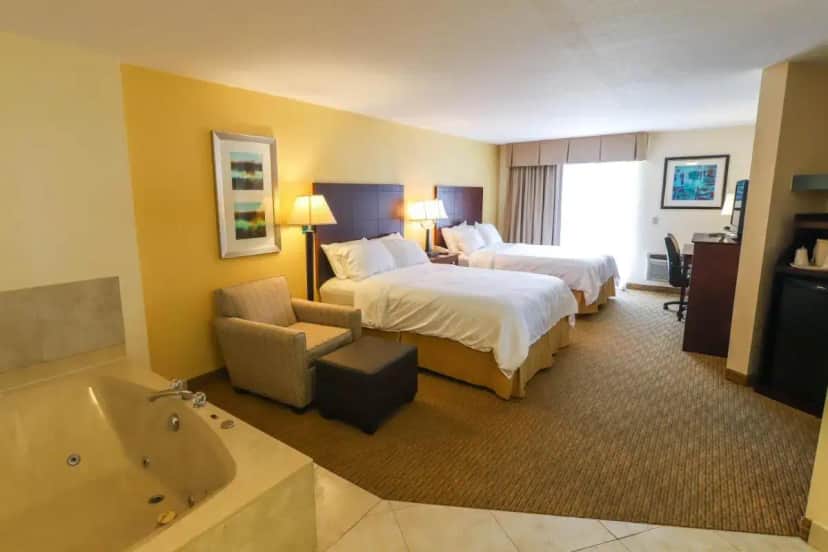a hotel room with two beds and a bath tub at Holiday Inn Express St. Ignace-Lake Front by IHG in Saint Ignace