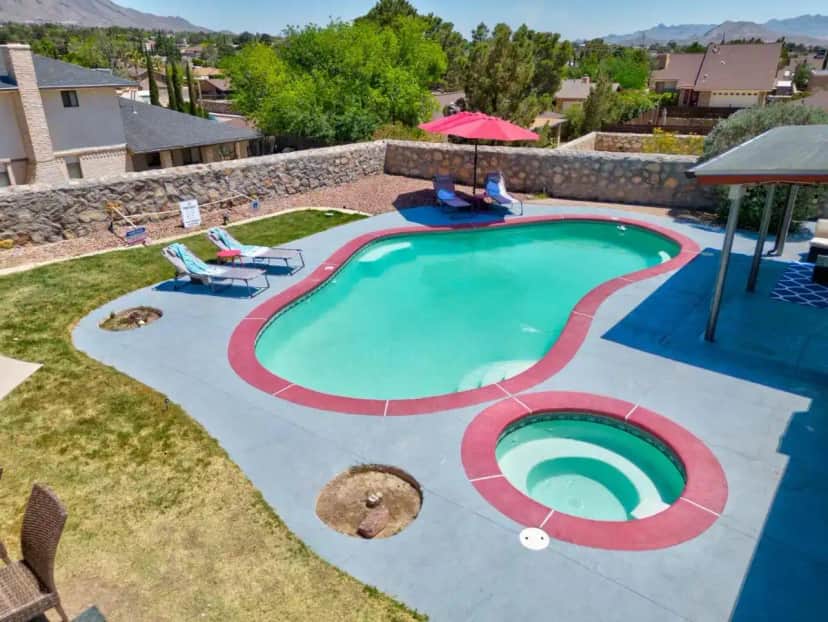 a swimming pool with chairs and an umbrella at Home with Mountain View/Pool/Tub in El Paso