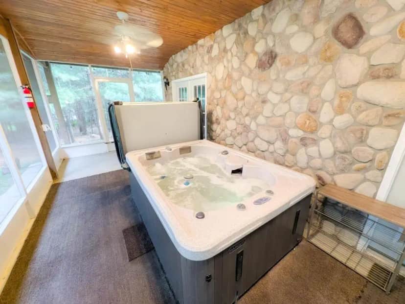 a large bath tub in a room with a stone wall at Hot Tub + Sauna + Game Room | Near Downtown Dells in Wisconsin Dells