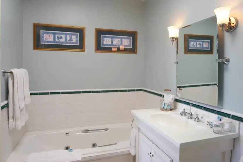 a white bathroom with a sink and a tub and a mirror at Hotel Mac in Richmond