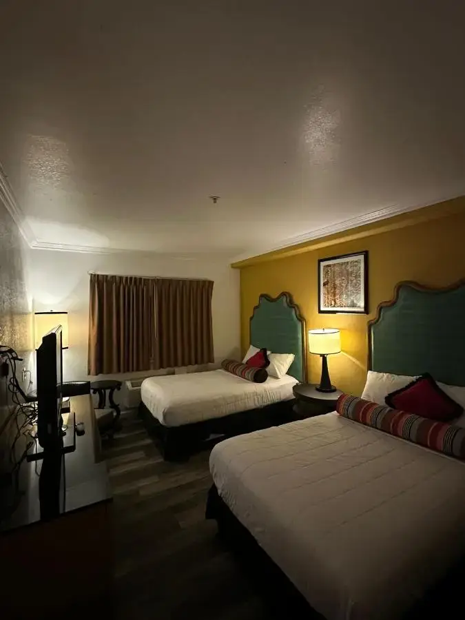 a hotel room with two beds and a desk at Howard Johnson by Wyndham Bakersfield in Bakersfield