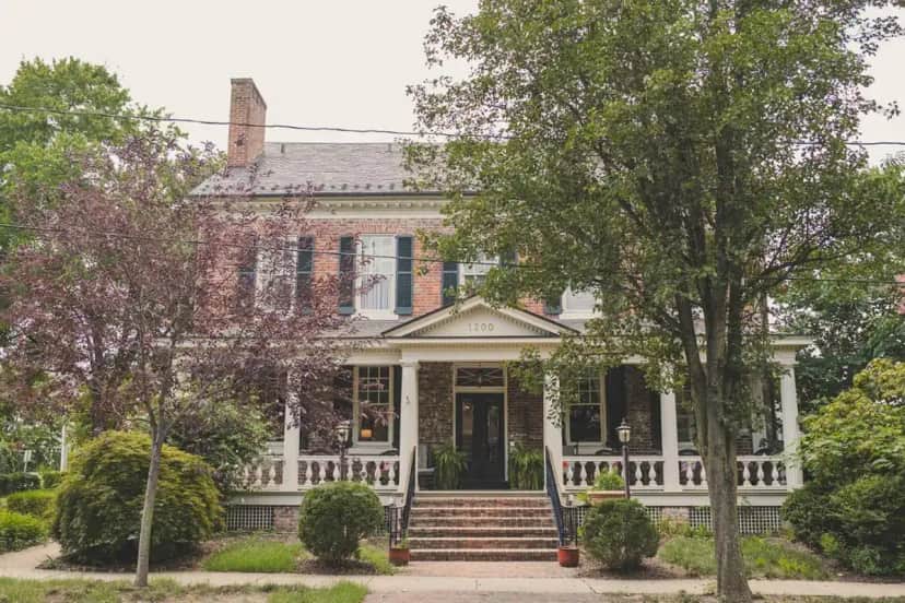 an old brick house with a white front porch at Ironclad Inn and Bourbon Room in Fredericksburg