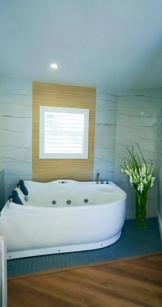 a white bath tub in a bathroom with a window at Ivory Sands Beach Suites in Clearwater Beach