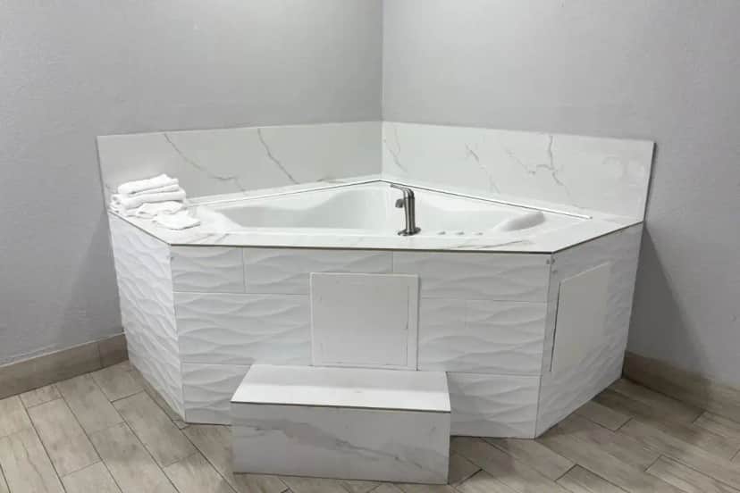 a white bath tub with a sink in a bathroom at Kiwi Inn Capital O Houston - Hwy 249 in Houston