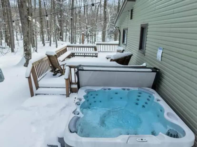 a hot tub on the back of a house in the snow at La Casita at Creekview in Gouldsboro