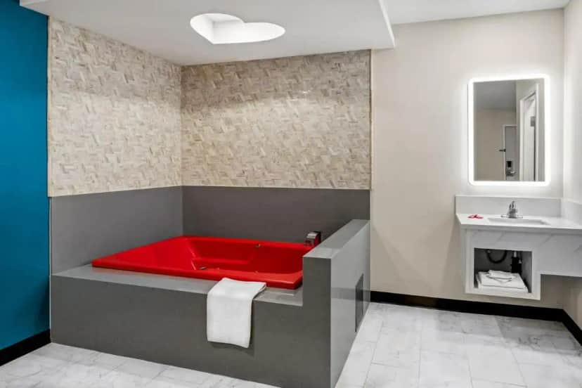 a bathroom with a red tub and a sink at La Mirage Inn - Long Beach in Long Beach