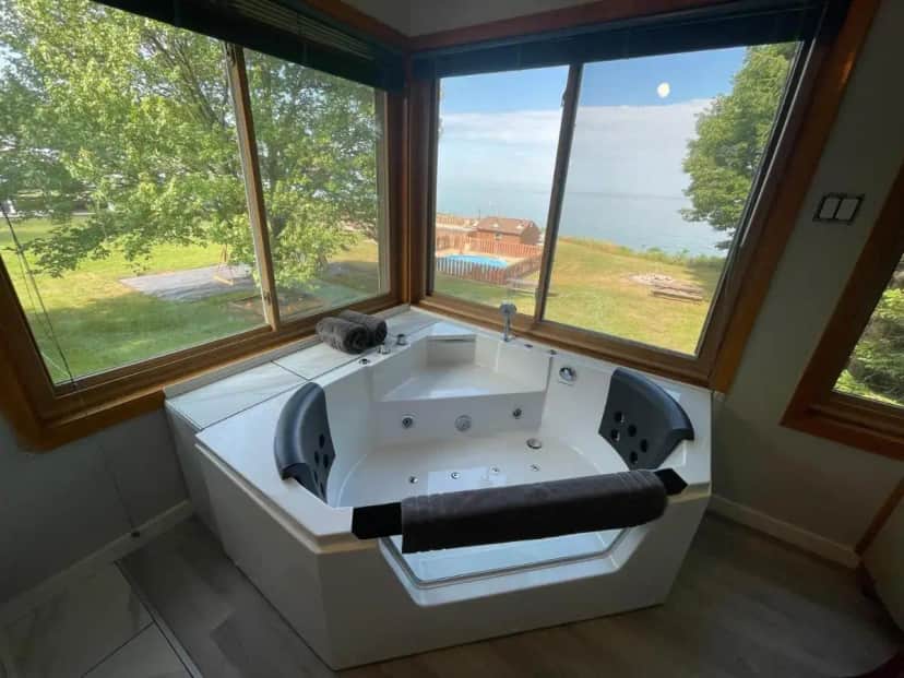 a large white bath tub in a room with windows at Lake Bluff Inn and Suites in South Haven
