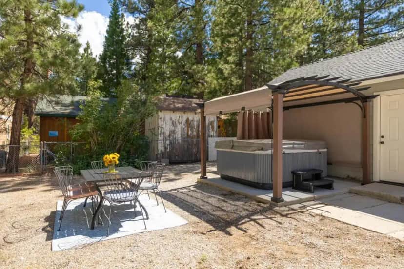 a backyard with a hot tub and a table and chairs at Bayview Bungalow - Cabin with Hot Tub One Block from Big Bear Lake! in Big Bear Lake