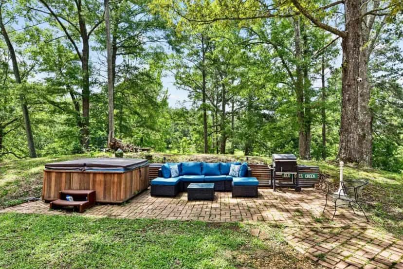 a patio with a blue couch and a hot tub at Lakefront Privacy - Pets, Hot Tub, Fishing, Boats in Meridian