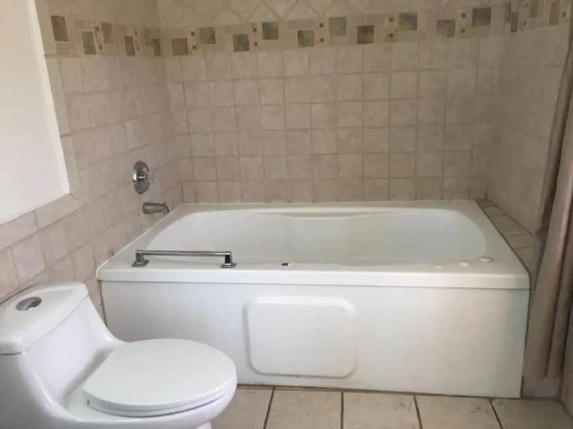 a bathroom with a white tub and a toilet at Main & Salt in Pismo Beach