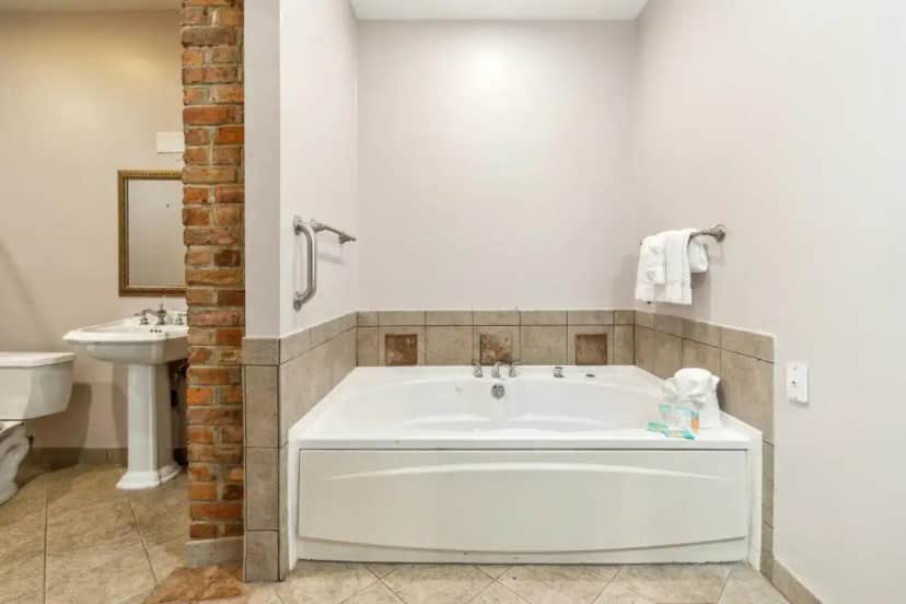 a white bath tub in a bathroom with a sink at Maison Saint Charles in New Orleans
