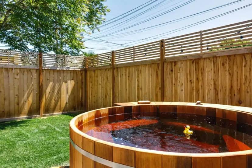 a wooden fence with a pond in a backyard at Maple Leaf Craftsman - Hot Tub, AC, Dog Friendly in Seattle