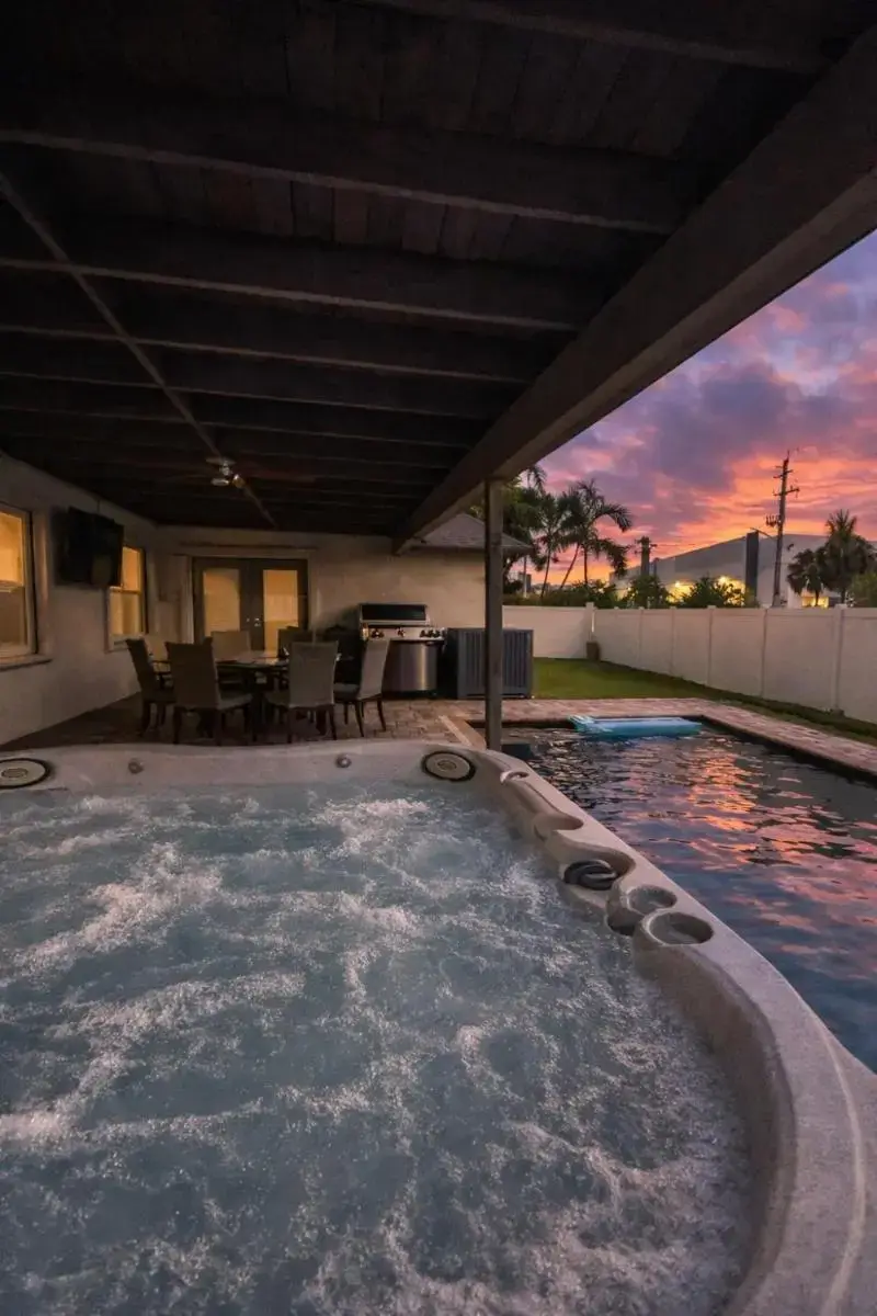 a jacuzzi tub in a backyard with a sunset at Modern 3BR Pool Home & Hot Tub Near Beach in Deerfield Beach