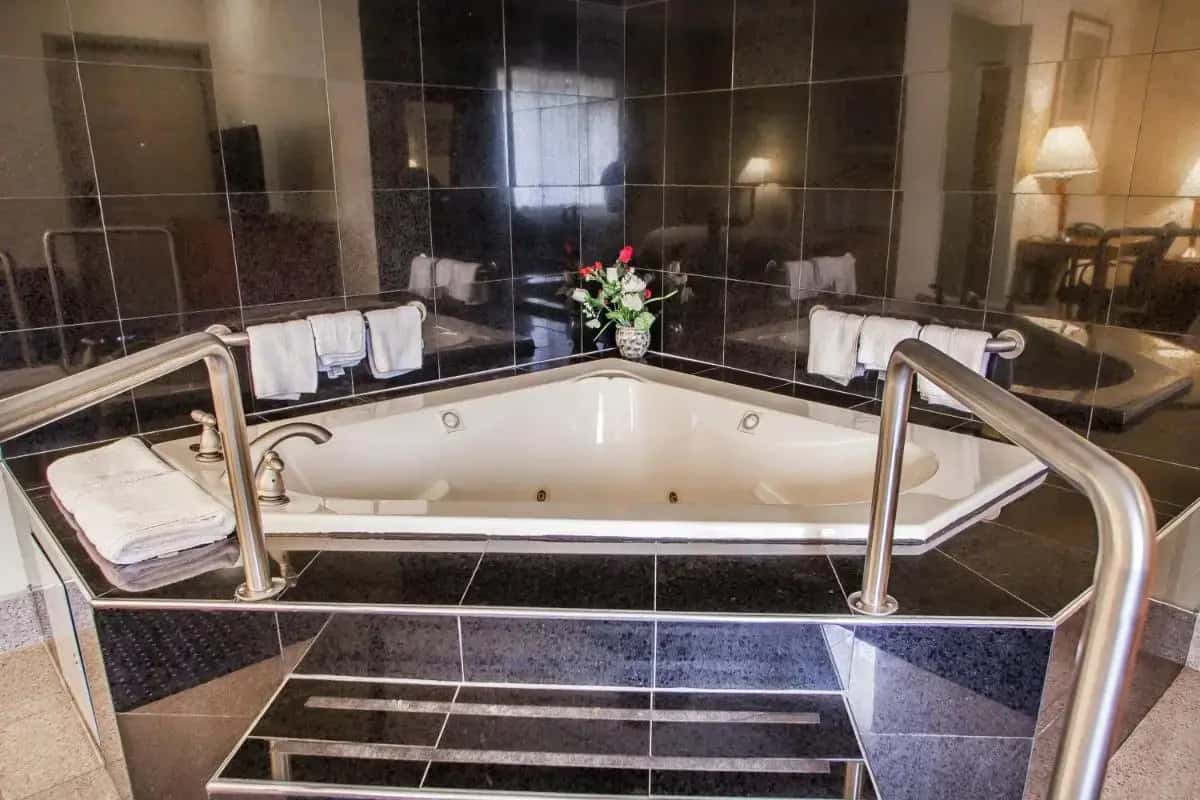 a bath tub in a bathroom with black tiles at Motel 6 East Windsor, NJ Hightstown in East Windsor