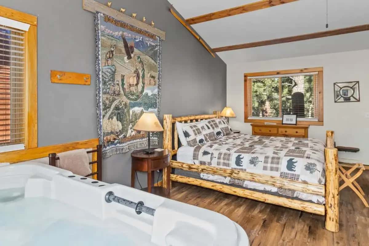 a bedroom with a bed and a tub and a window at Mountain Shadows Cabins in Estes Park
