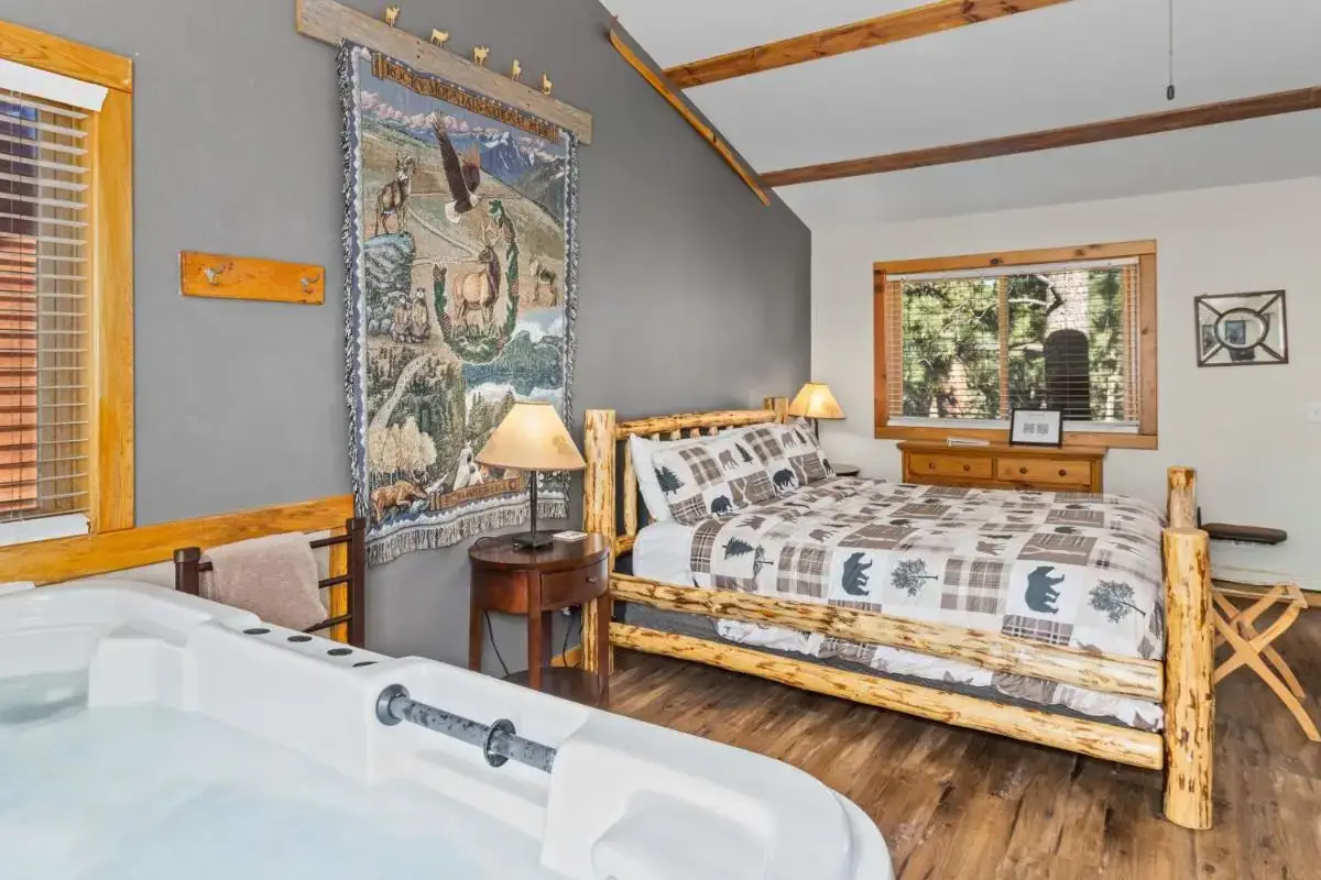 a bedroom with a bed and a tub and a window at Mountain Shadows Cabins in Estes Park