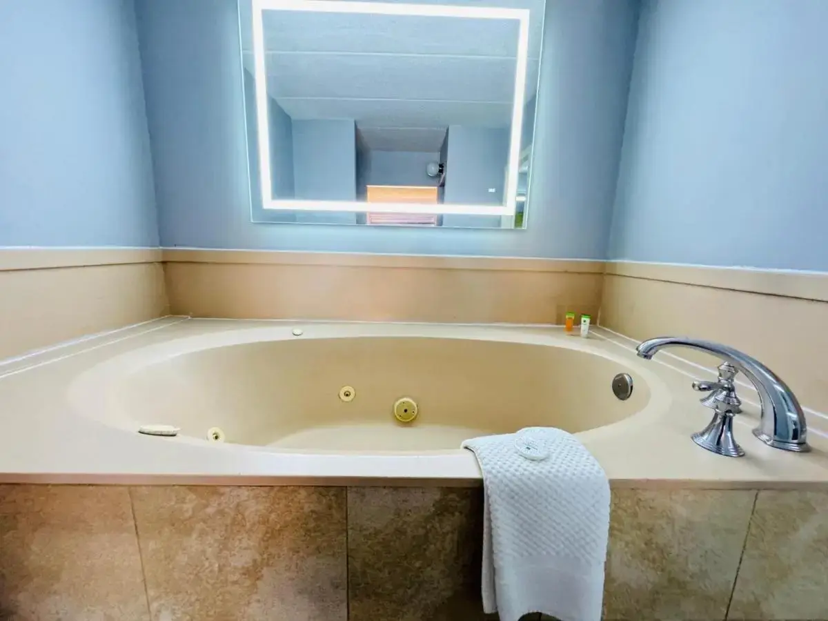 a bath tub in a bathroom with a mirror at Mystic River Hotel & Suites in Mystic