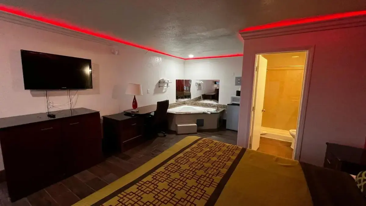 a room with a bedroom with a bed and a television at New American Inn & Suites in Anaheim