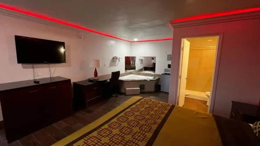 a room with a bedroom with a bed and a television at New American Inn & Suites in Anaheim