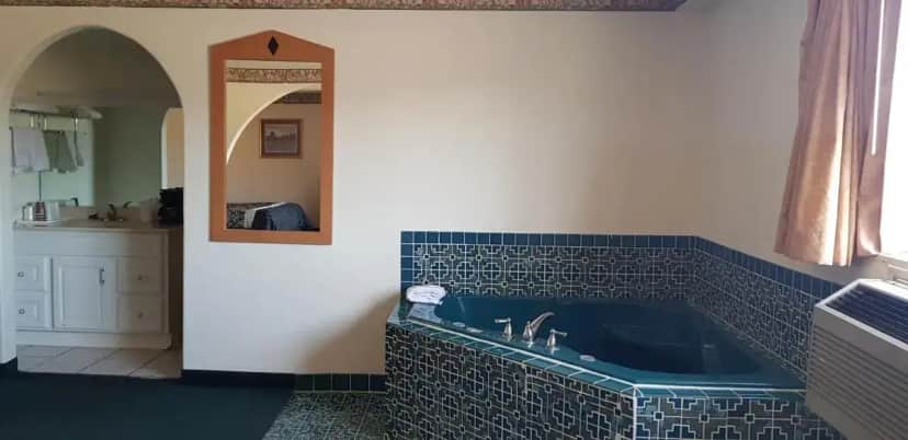 a bathroom with a blue tiled tub with a sink at Night Inn in Globe