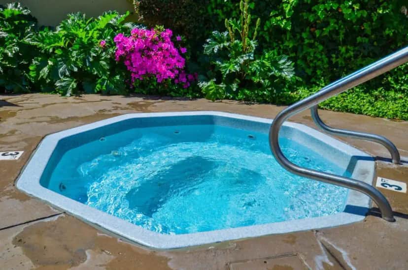 a hot tub in a yard with flowers at Ocean Pacific Lodge in Santa Cruz
