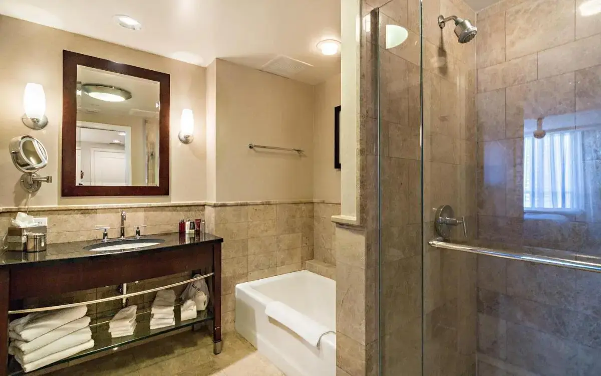 a bathroom with a tub and a sink and a shower at Oceanfront Palm Beach Resort & Spa Singer Island in Riviera Beach