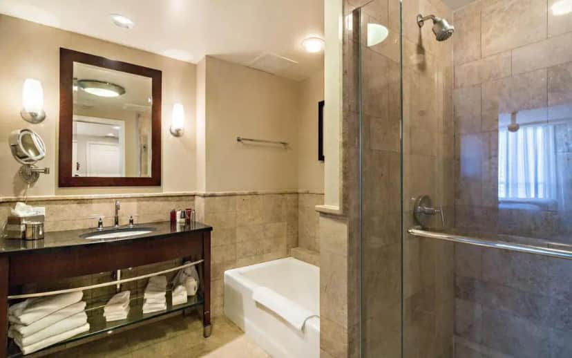 a bathroom with a tub and a sink and a shower at Oceanfront Palm Beach Resort & Spa Singer Island in Riviera Beach
