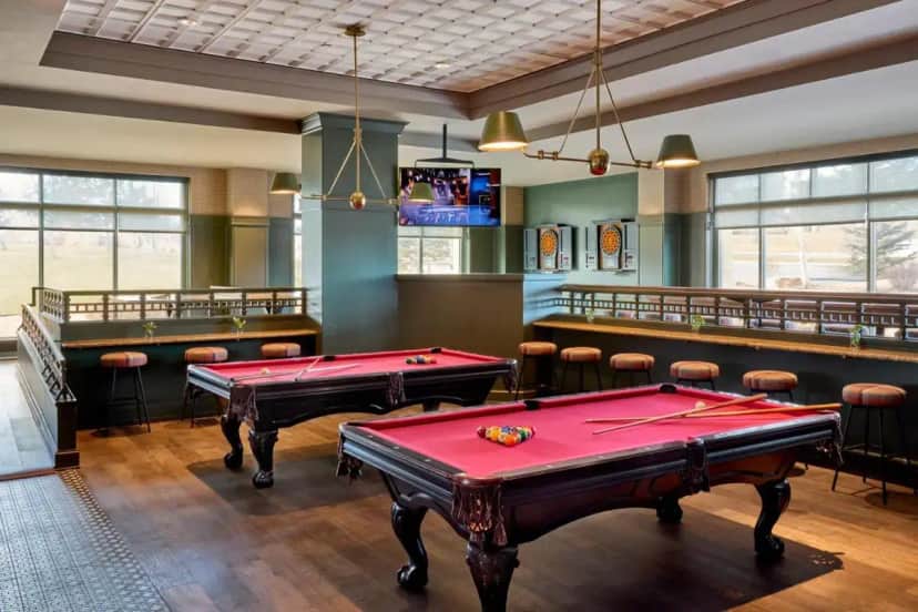a billiard room with two pool tables and chairs at Omni Interlocken Hotel in Broomfield