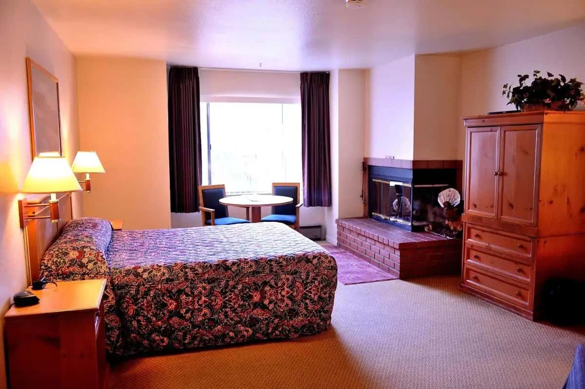 a hotel room with a bed and a fireplace at Pacific Gardens Inn in Pacific Grove