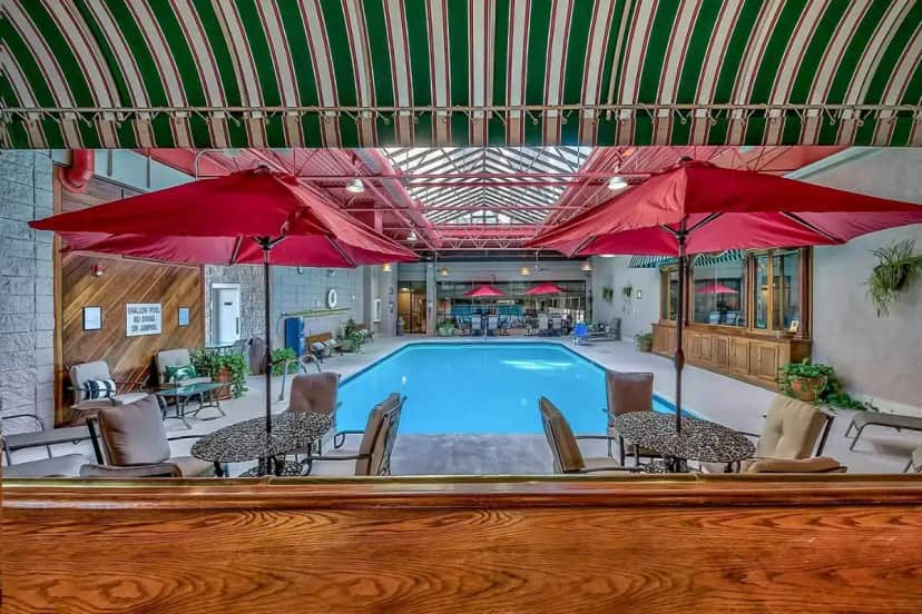 a pool with red umbrellas and tables and chairs at Plaza Resort Club Reno in Reno