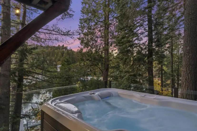 a jacuzzi tub with a view of the forest at Private Dock Swim and Fish Hot TUB Rocky Point Surreal location in Lake Arrowhead