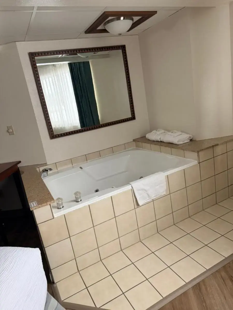 a bath tub in a bathroom with a mirror at Quality Inn & Suites Black River Falls I-94 in Black River Falls