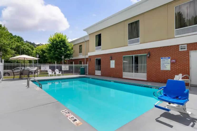 a swimming pool with a blue chair in front of a building at Quality Inn & Suites Decatur - Atlanta East in Fairington