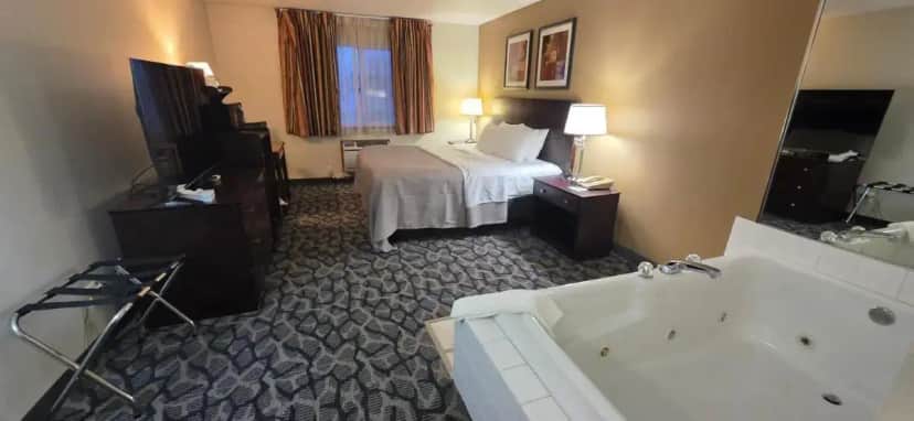 a hotel room with a bed and a bath tub at Quality Inn & Suites Eldridge Davenport North in Eldridge