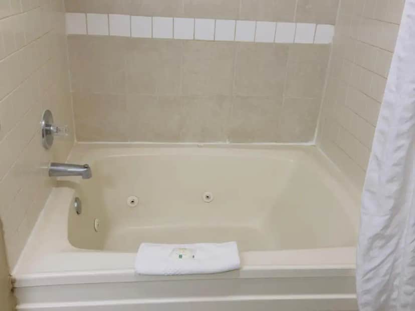 a bathroom with a bath tub with a towel at Quality Inn & Suites Seville in Seville