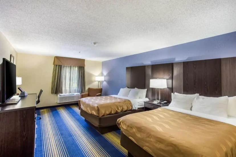 a hotel room with two beds and a flat screen tv at Quality Inn Charleston South in Charleston