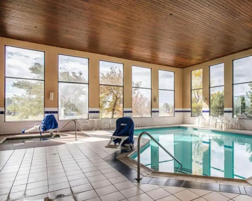 a swimming pool with two chairs and a table at Quality Inn Colorado Springs Airport in Colorado Springs