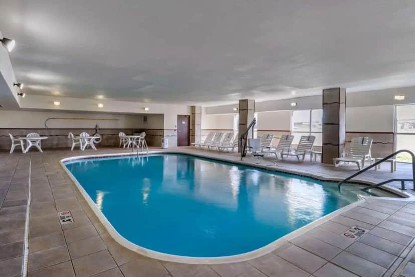 a pool in a hotel with chairs and tables at Quality Suites Addison-Dallas in Addison