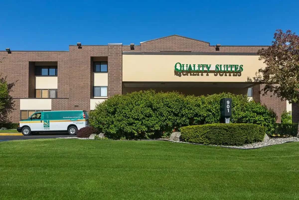 a building with a van parked in front of it at Quality Suites Lansing West in Lansing